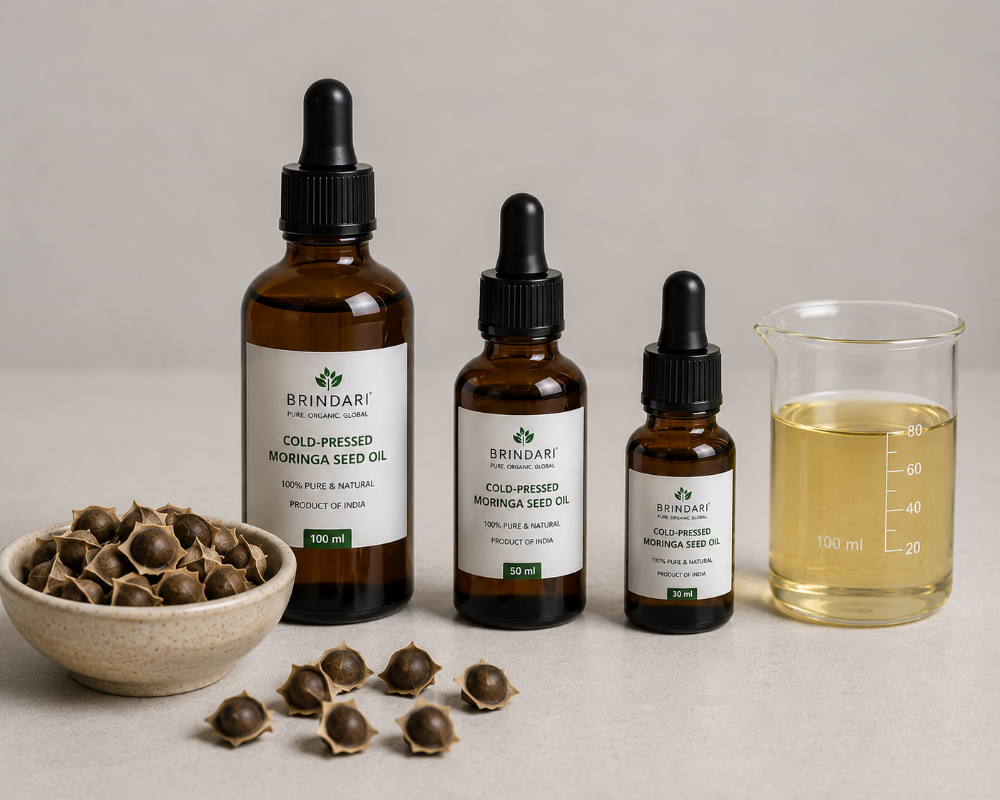 Cold-pressed moringa seed oil in amber dropper bottles beside a bowl of moringa seeds and a beaker of oil